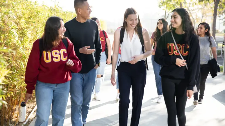 Four USC students walking on campus wearing USC branded attire.